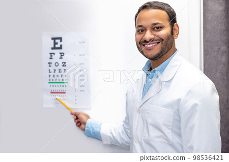 Smiling male doctor standing near eyesight check list 98536421