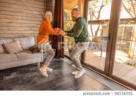 Happy couple dancing at home and looking energized and excited 98536585