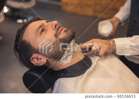 Barber applying foam on the clients neck before shaving Barber applying foam on the clients neck before shaving 98536655