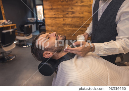 Barber applying foam on the clients neck before shaving Barber applying foam on the clients neck before shaving 98536660
