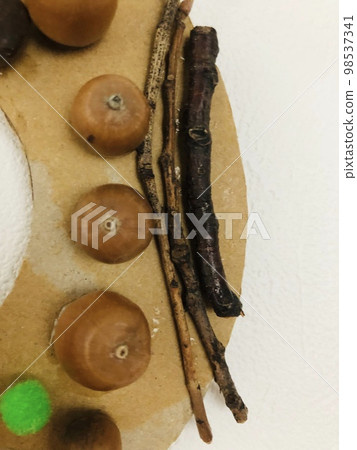 一張紙板花環的照片,上面裝飾著與秋天相關的物品,例如橡子和樹枝。 一張紙板花環的照片,上面裝飾著與秋天相關的物品,例如橡子和樹枝。 98537341