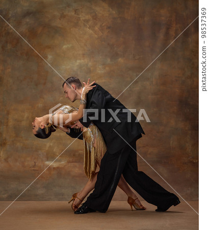 Passionate man and woman, professional dancers in stylish stage costumes performing ballroom, tango dance over dark vintage background Passionate man and woman, professional dancers in stylish stage costumes performing ballroom, tango dance over dark vintage background 98537369