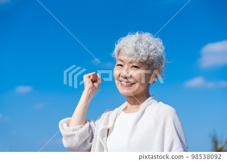 一位資深女性在藍天下做膽量姿勢 一位資深女性在藍天下做膽量姿勢 98538092