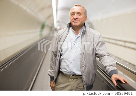 Middle aged man on moving walkway Middle aged man on moving walkway 98539491
