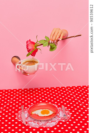 Food pop art photography. Female hand sticking out pink paper with coffee cup and rose flower. Fried eggs for breakfast 98539612