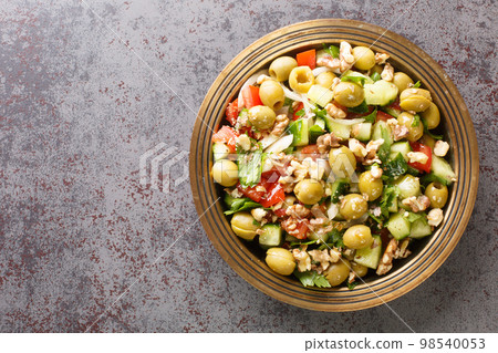 Healthy vegetarian vegetable salad with green olives, walnuts, tomatoes, cucumbers, parsley close-up in a plate. Horizontal top view Healthy vegetarian vegetable salad with green olives, walnuts, tomatoes, cucumbers, parsley close-up in a plate. Horizontal top view 98540053