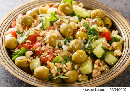 Healthy vegetarian vegetable salad with green olives, walnuts, tomatoes, cucumbers, parsley close-up in a plate. Horizontal Healthy vegetarian vegetable salad with green olives, walnuts, tomatoes, cucumbers, parsley close-up in a plate. Horizontal 98540062
