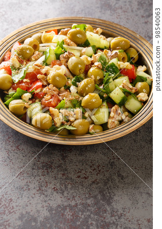 Green olive salad yesil zeytin salatasi with vegetables closeup on the plate. Vertical 98540063