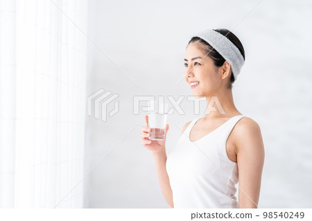 一個女人在窗邊喝水。 一個女人在窗邊喝水。 98540249