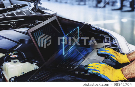 Technician is tuning engine car with a computer software of the laptop in auto repair garage 98541704