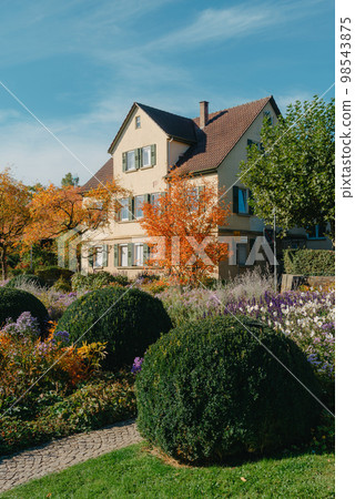 House with nice garden in fall. Flowers in the City Park of Bietigheim-Bissingen, Baden-Wuerttemberg, Germany, Europe. Autumn Park and house, nobody, bush and grenery 98543875