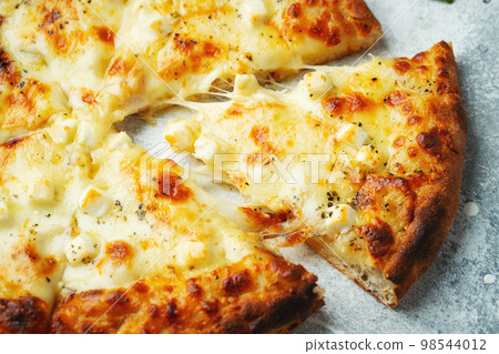 Italian pizza four cheeses with stretching cheese and basil on a light concrete background Italian pizza four cheeses with stretching cheese and basil on a light concrete background 98544012