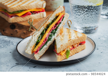 Two homemade sandwiches with sausage, cheese and arugula on a light concrete background 98544024