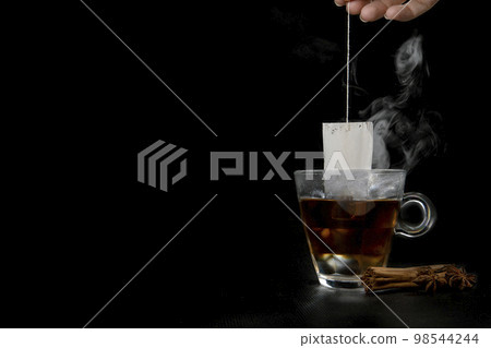Glass of hot tea with tea bag hanging black background copy space, Glass of hot tea with tea bag hanging black background copy space, 98544244