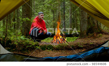 Bearded man by the fire in a beautiful forest. Bearded man by the fire in a beautiful forest. 98544606