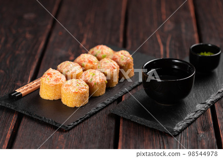 Sushi roll with mayonnaise sauce served on black board and soy sauce. 98544978