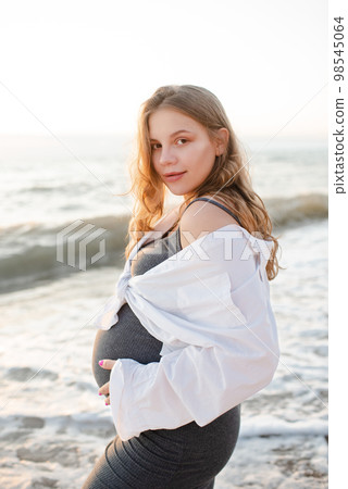 Pregnant woman 20-24 year old wear casual dress and shirt over sea nature background outdoor. Motherhood. Maternity. Pregnant woman 20-24 year old wear casual dress and shirt over sea nature background outdoor. Motherhood. Maternity. 98545064