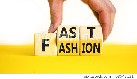 Fast fashion symbol. Concept words Fast fashion on wooden cubes. Beautiful yellow table white background. Businessman hand. Business fast fashion concept. Copy space. 98545131