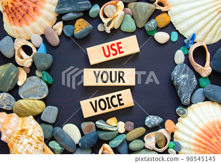 Use your voice symbol. Concept words Use your voice on wooden blocks on a beautiful black table black background. Sea shell and stone. Business and use your voice concept. Copy space. Use your voice symbol. Concept words Use your voice on wooden blocks on a beautiful black table black background. Sea shell and stone. Business and use your voice concept. Copy space. 98545145