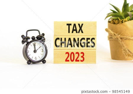 Tax changes 2023 symbol. Concept words Tax changes 2023 on wooden blocks on a beautiful white table white background. Black alarm clock. House plant. Business Tax changes 2023 concept. Copy space. 98545149