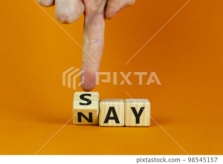 Say nay symbol. Businessman turns a cube, changes the word 'say' to 'nay'. Beautiful orange background. Copy space. Business, motivation and say nay concept. 98545157