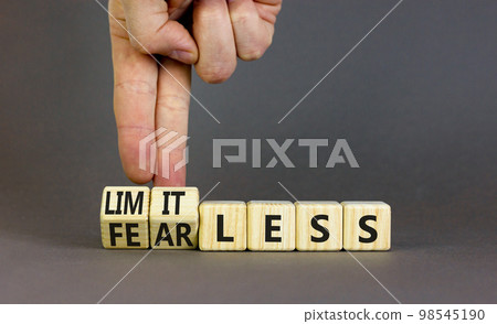 Fearless and limitless symbol. Concept word Fearless and limitless on wooden cubes. Businessman hand. Beautiful grey table grey background. Business fearless and limitless concept. Copy space. 98545190