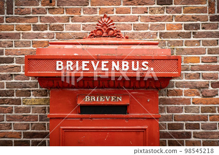 traditional old Dutch red postbox mounted in a cotswold stone wall 98545218