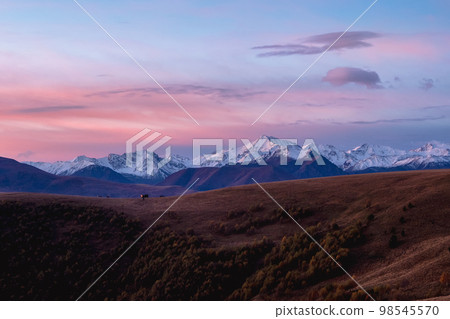 Contrasting mountains at sunset. Purple sunset over majestic mountains. Sunset in magenta tones. Atmospheric purple landscape with a high-altitude snowy mountain valley. Contrasting mountains at sunset. Purple sunset over majestic mountains. Sunset in magenta tones. Atmospheric purple landscape with a high-altitude snowy mountain valley. 98545570