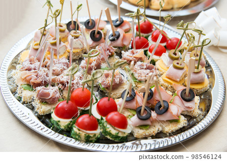 The buffet at the reception. Assortment of canapes. Banquet service. Catering, snacks with different types of cheese and meat. Party Concept. The buffet at the reception. Assortment of canapes. Banquet service. Catering, snacks with different types of cheese and meat. Party Concept. 98546124