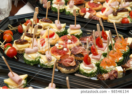 The buffet at the reception. Assortment of canapes. Banquet service. Catering, snacks with different types of cheese and meat. Party Concept. The buffet at the reception. Assortment of canapes. Banquet service. Catering, snacks with different types of cheese and meat. Party Concept. 98546134