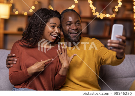 Happy black couple got engaged, taking selfie on smartphone together Happy black couple got engaged, taking selfie on smartphone together 98546280