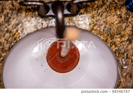 Using a plunger on a bathroom sink plugged with Hair and scum in a pool of stagnant standing water. 98546787
