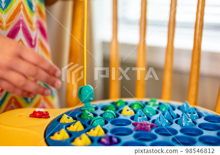 Children's game of using a miniature pole and line lowered into open plastic fish to catch them as the pond spins. Children's game of using a miniature pole and line lowered into open plastic fish to catch them as the pond spins. 98546812