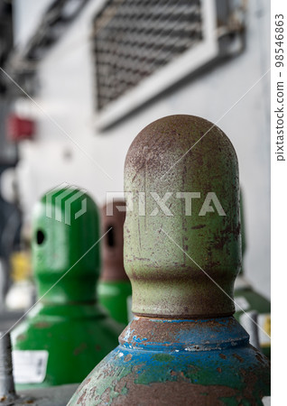 Compressed gas cylinders being stored vertically secured by a metal chain and a metal cap. 98546863