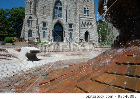 Omaha, Nebraska, US - 5.2022 - Selective focus on fountain in front of St. John's Parish Catholic Church on the campus of Creighton University. Omaha, Nebraska, US - 5.2022 - Selective focus on fountain in front of St. John's Parish Catholic Church on the campus of Creighton University. 98546895