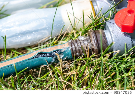 Frayed garden hose with burst section spraying water from the point of connection Frayed garden hose with burst section spraying water from the point of connection 98547056