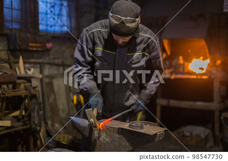 Blacksmith forging molten metal Blacksmith forging molten metal 98547730