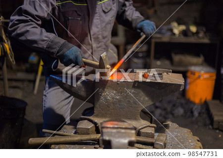 Blacksmith forging molten metal 98547731
