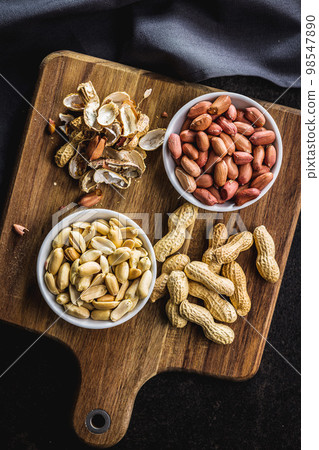 Unpeeled and peeled peanuts in bowl on kitchen table. Top view. 98547890