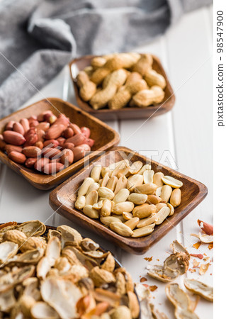 Unpeeled and peeled peanuts in bowl on kitchen table. Unpeeled and peeled peanuts in bowl on kitchen table. 98547900