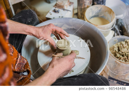 Professional potter shaping mug in pottery workshop 98548486