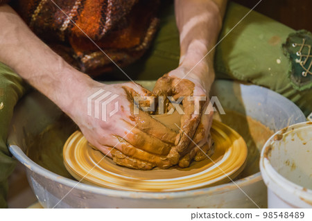 Close up view - professional male potter working with clay on pottery wheel 98548489
