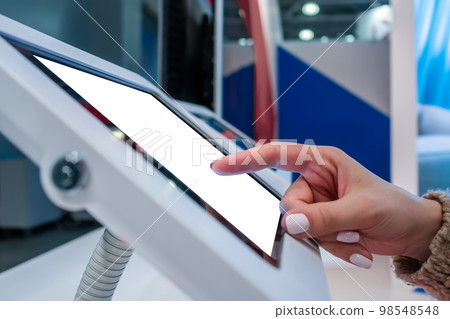 Woman touching white blank display of electronic tablet kiosk - mockup image Woman touching white blank display of electronic tablet kiosk - mockup image 98548548