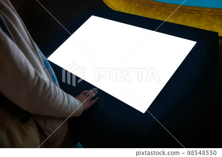 Woman using interactive empty white touchscreen display kiosk at exhibition Woman using interactive empty white touchscreen display kiosk at exhibition 98548550