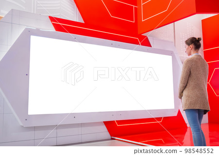 Woman looking at empty white large wall display at trade show - mockup image 98548552