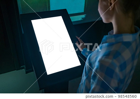 Woman using interactive white empty touchscreen display kiosk at exhibition 98548560
