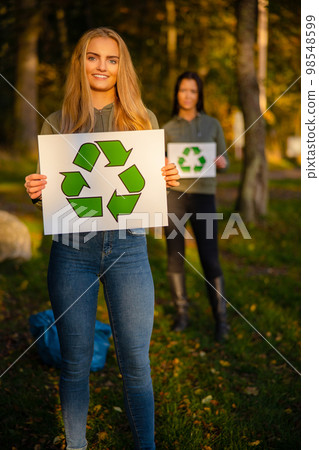 Smiling woman holding recycling symbol placard togheter with her team Smiling woman holding recycling symbol placard togheter with her team 98548599