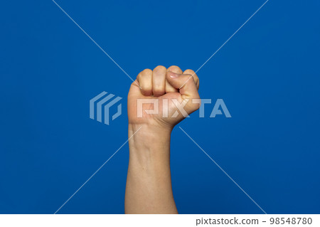 Man's fist seized with power isolated on blue background. Symbol of rebellion and uprising of the working classes oppressed by the elites. 98548780