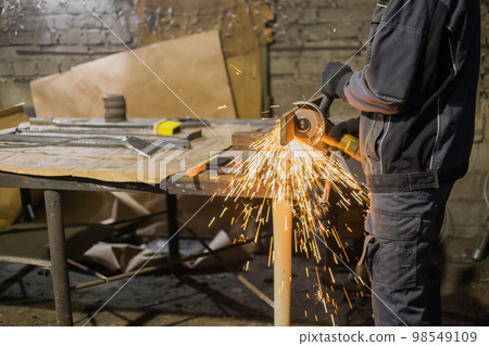 Blacksmith sawing metal with hand circular saw Blacksmith sawing metal with hand circular saw 98549109