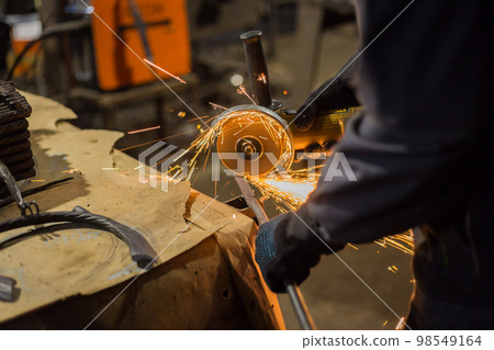 Blacksmith sawing metal with hand circular saw 98549164